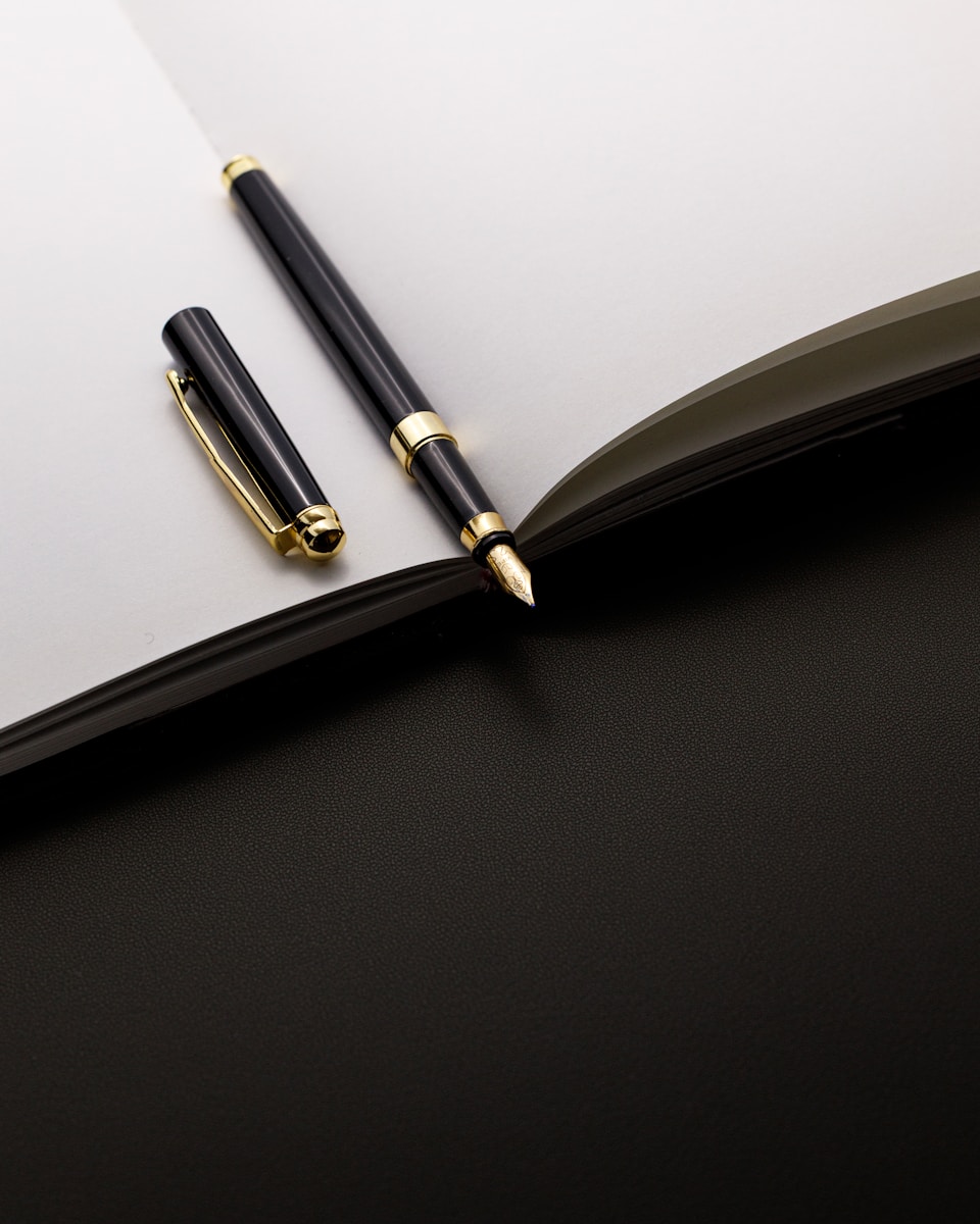 A black and gold pen rests on an open notebook.